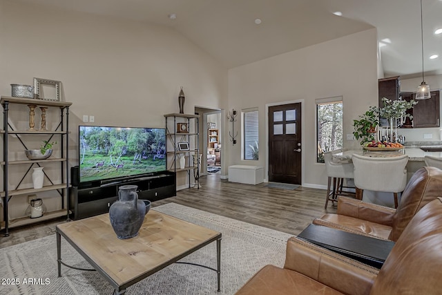 living room featuring light wood-style floors, baseboards, high vaulted ceiling, and recessed lighting