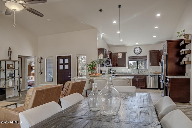 dining space with light wood-style floors, ceiling fan, high vaulted ceiling, and recessed lighting