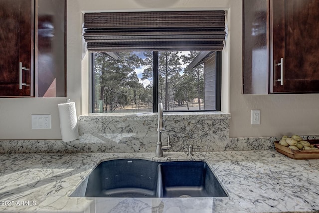 interior space with light stone counters, a sink, and dark brown cabinetry