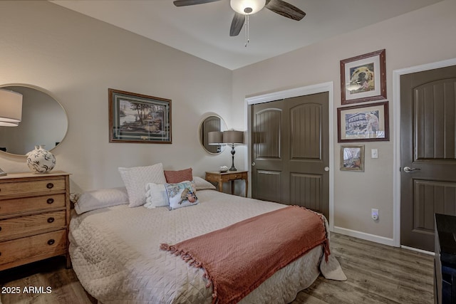 bedroom with a closet, wood finished floors, a ceiling fan, and baseboards