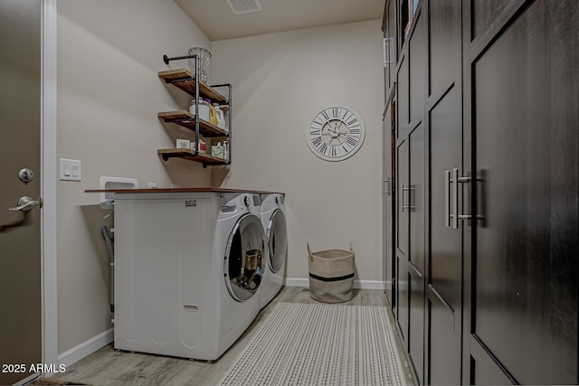 laundry area with laundry area, baseboards, light wood-style floors, and washer and dryer