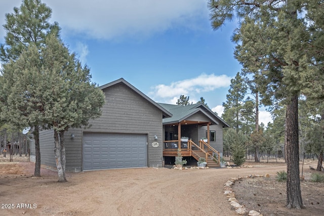 view of front of home with a porch, a garage, and dirt driveway