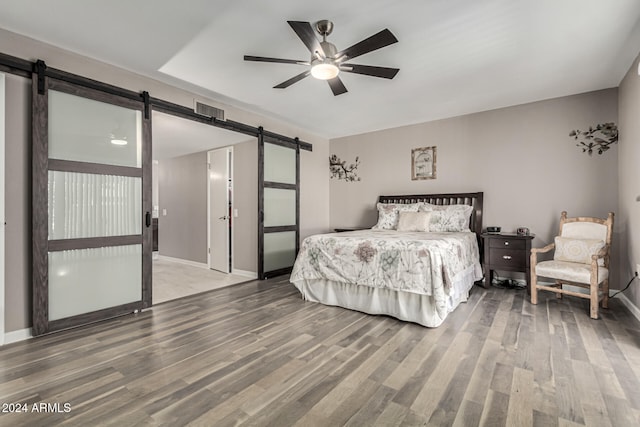 bedroom featuring a barn door, ceiling fan, and wood-type flooring