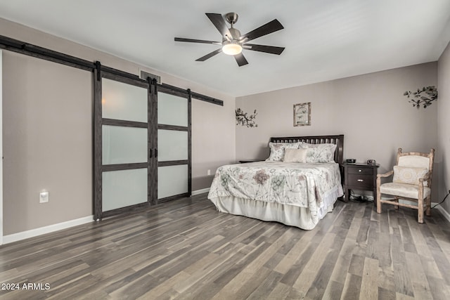 bedroom featuring a barn door, ceiling fan, and dark hardwood / wood-style floors