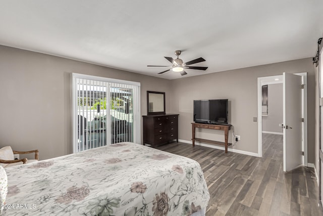 bedroom with access to exterior, dark hardwood / wood-style flooring, a barn door, and ceiling fan