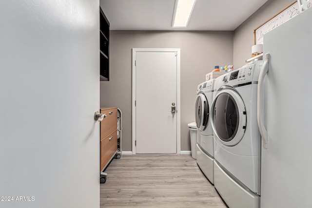 laundry room with washer and dryer and light hardwood / wood-style floors