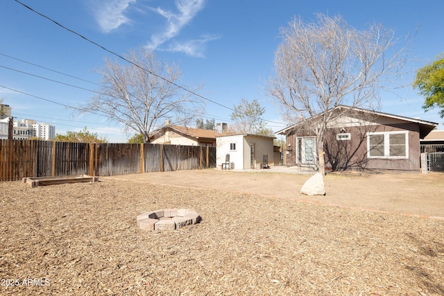 back of property with a patio, an outdoor structure, and an outdoor fire pit