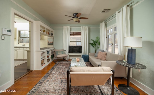 living area with wood-type flooring, sink, and ceiling fan