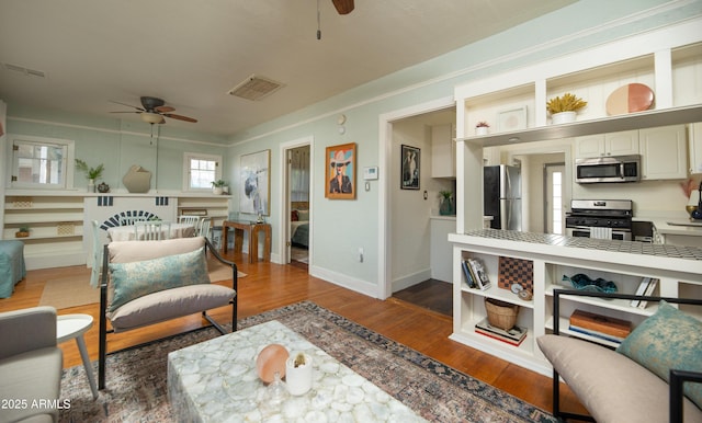 living room with crown molding, dark hardwood / wood-style floors, and ceiling fan