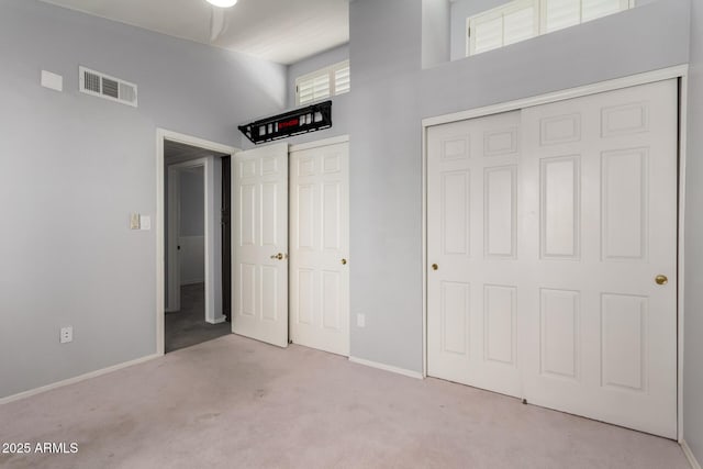 unfurnished bedroom with light colored carpet and a high ceiling