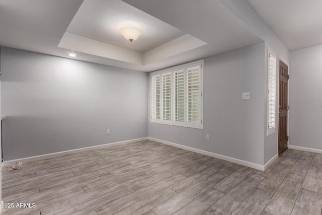 unfurnished room featuring a raised ceiling and light wood-type flooring