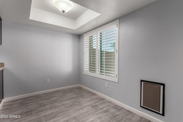 unfurnished room featuring a tray ceiling and light hardwood / wood-style flooring