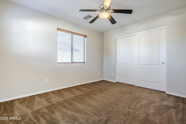 unfurnished bedroom featuring dark colored carpet, ceiling fan, and a closet