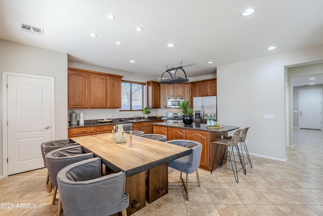 kitchen featuring sink, a kitchen island, light tile patterned floors, and appliances with stainless steel finishes