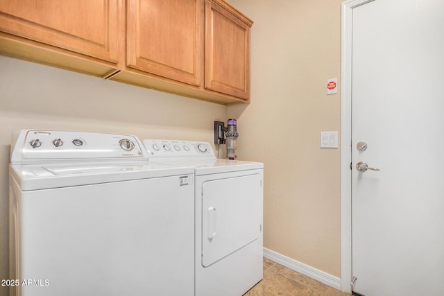 clothes washing area with cabinets, washing machine and clothes dryer, and light tile patterned flooring