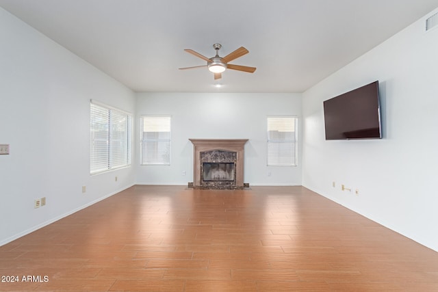 unfurnished living room with ceiling fan, hardwood / wood-style flooring, and a premium fireplace