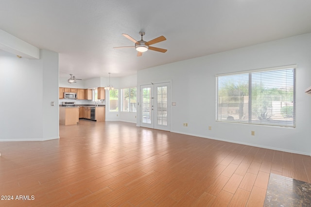 unfurnished living room with french doors, light wood-type flooring, and ceiling fan