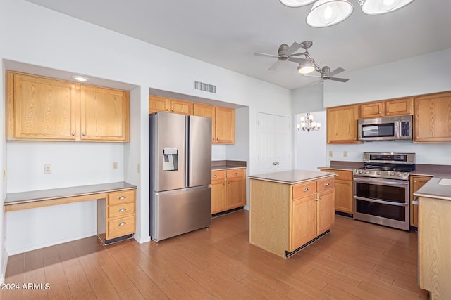 kitchen with appliances with stainless steel finishes, ceiling fan, light hardwood / wood-style floors, and a kitchen island