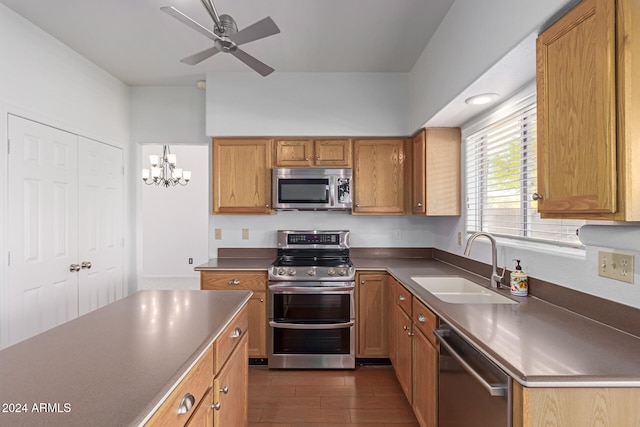 kitchen with ceiling fan with notable chandelier, stainless steel appliances, sink, and dark hardwood / wood-style floors