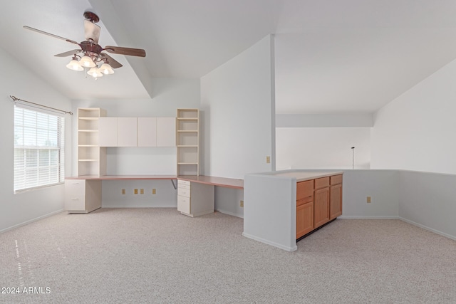 interior space with built in desk, kitchen peninsula, vaulted ceiling, light colored carpet, and ceiling fan