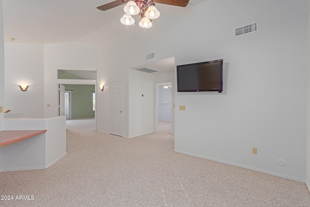 carpeted spare room featuring ceiling fan and a towering ceiling