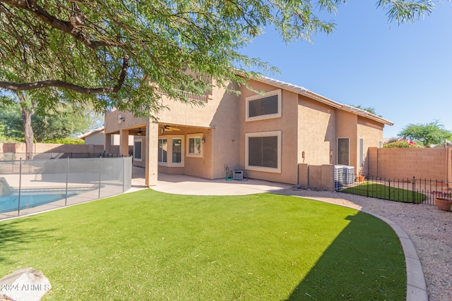 rear view of house with a patio area, a fenced in pool, and a lawn