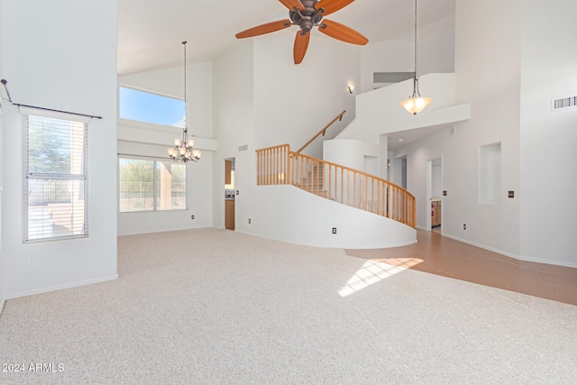 unfurnished living room featuring carpet, ceiling fan with notable chandelier, and high vaulted ceiling