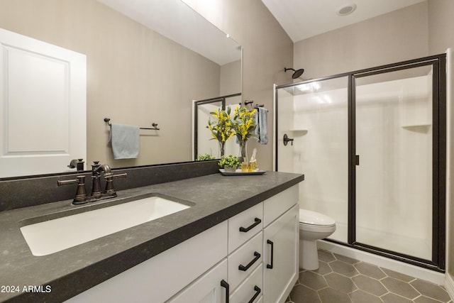 bathroom featuring toilet, a shower with door, vanity, and tile patterned flooring