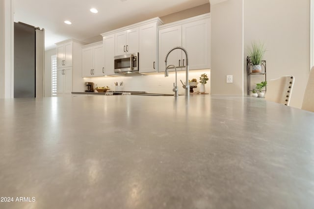 kitchen featuring backsplash, stainless steel appliances, sink, concrete floors, and white cabinetry