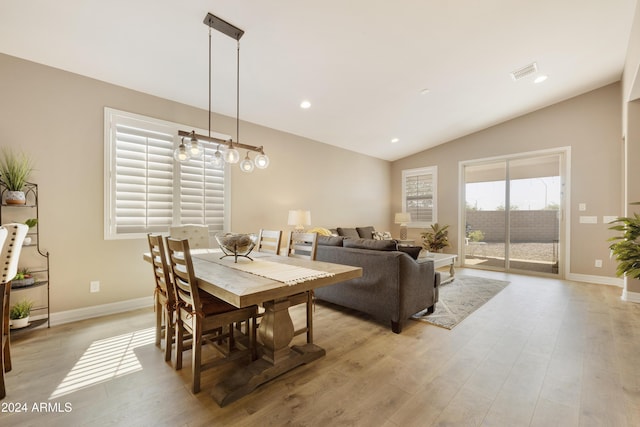 dining space with vaulted ceiling and light wood-type flooring