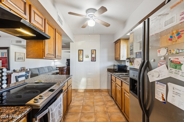 kitchen featuring light tile patterned floors, ceiling fan, appliances with stainless steel finishes, range hood, and dark stone countertops