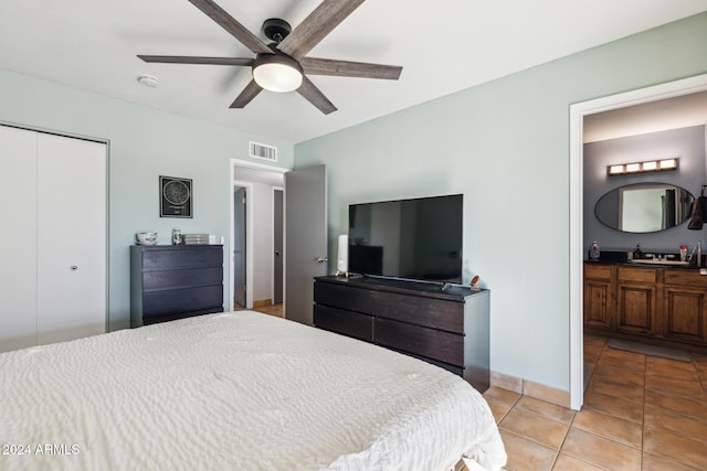 bedroom featuring ensuite bath, sink, ceiling fan, light tile patterned floors, and a closet