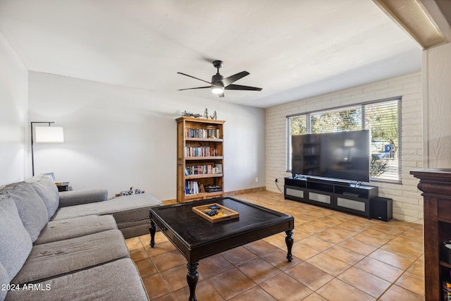 tiled living room with ceiling fan and brick wall