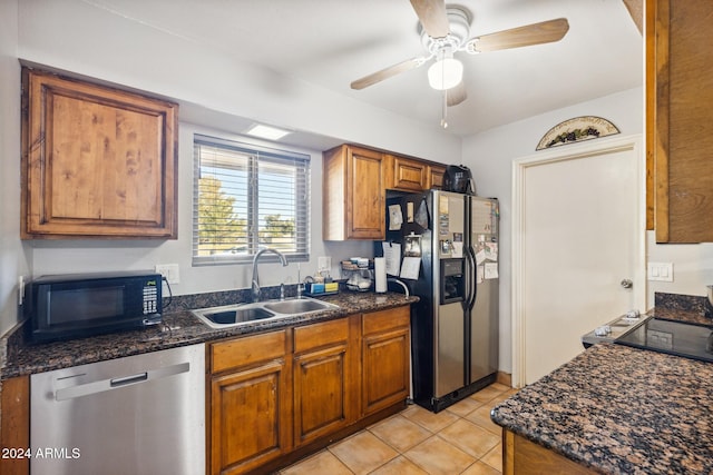 kitchen with sink, light tile patterned floors, ceiling fan, appliances with stainless steel finishes, and dark stone countertops