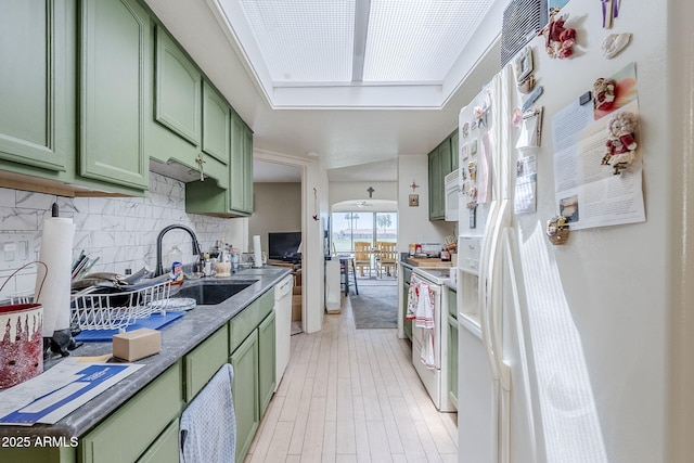 kitchen with a sink, green cabinetry, and white appliances