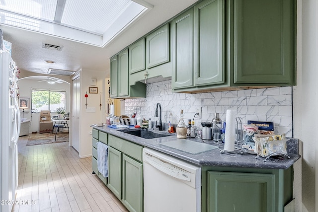 kitchen featuring backsplash, visible vents, a sink, green cabinets, and white appliances