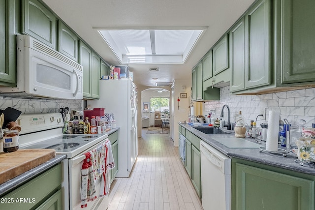 kitchen featuring white appliances, a sink, decorative backsplash, and green cabinets