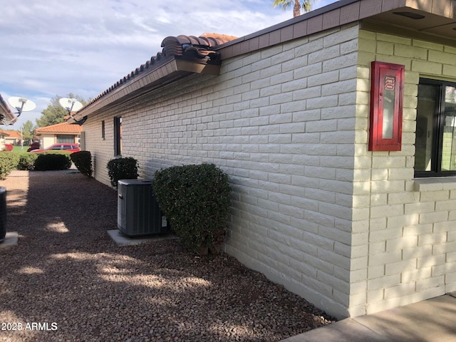view of home's exterior featuring a tiled roof and cooling unit
