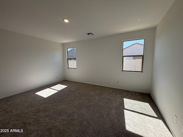 carpeted spare room featuring visible vents and baseboards