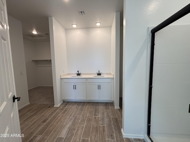 bathroom featuring visible vents, a walk in closet, wood tiled floor, and a sink