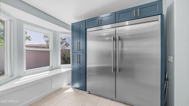 kitchen featuring stainless steel built in refrigerator, blue cabinetry, and light tile patterned floors