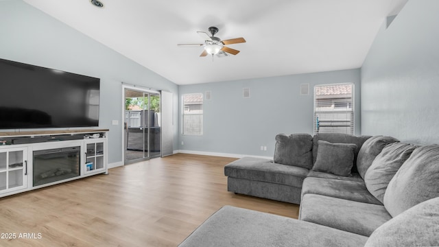 living area featuring vaulted ceiling, ceiling fan, wood finished floors, and baseboards