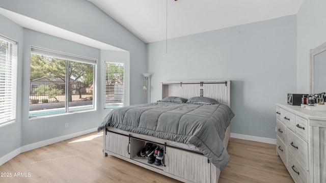 bedroom with multiple windows, lofted ceiling, baseboards, and light wood finished floors