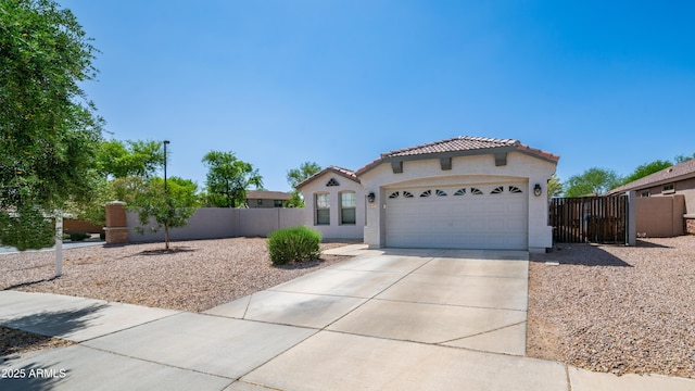 mediterranean / spanish-style house with stucco siding, a tiled roof, concrete driveway, a garage, and fence