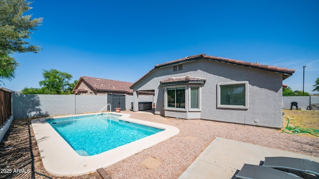 view of swimming pool with a fenced backyard, a patio, a shed, and an outbuilding