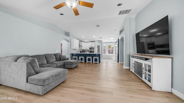 living room featuring arched walkways, a ceiling fan, vaulted ceiling, light wood-type flooring, and recessed lighting