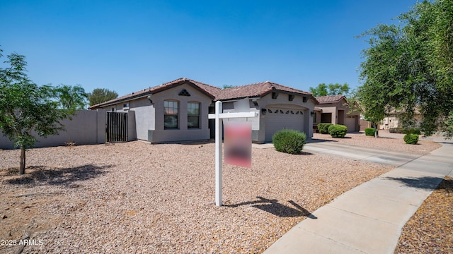 mediterranean / spanish-style home with stucco siding, an attached garage, fence, and a tiled roof