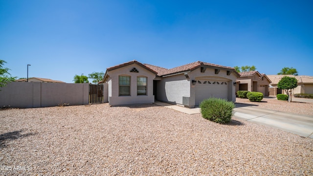 mediterranean / spanish-style home with a tile roof, stucco siding, an attached garage, concrete driveway, and fence