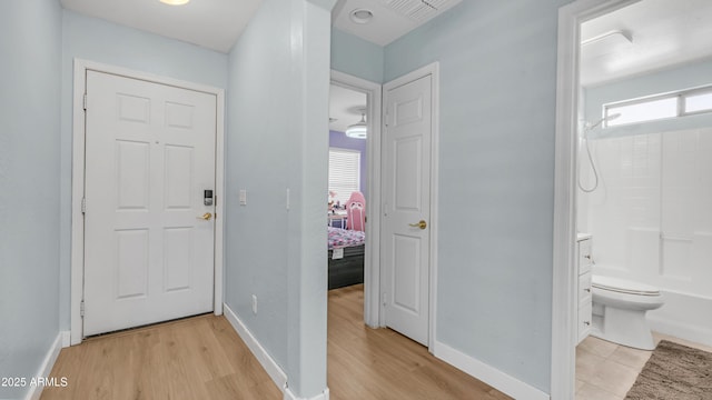 hall featuring light wood-style flooring and baseboards