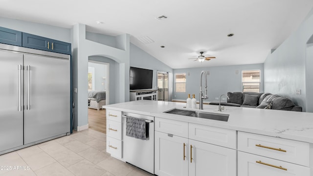 kitchen with stainless steel appliances, a sink, vaulted ceiling, open floor plan, and a ceiling fan
